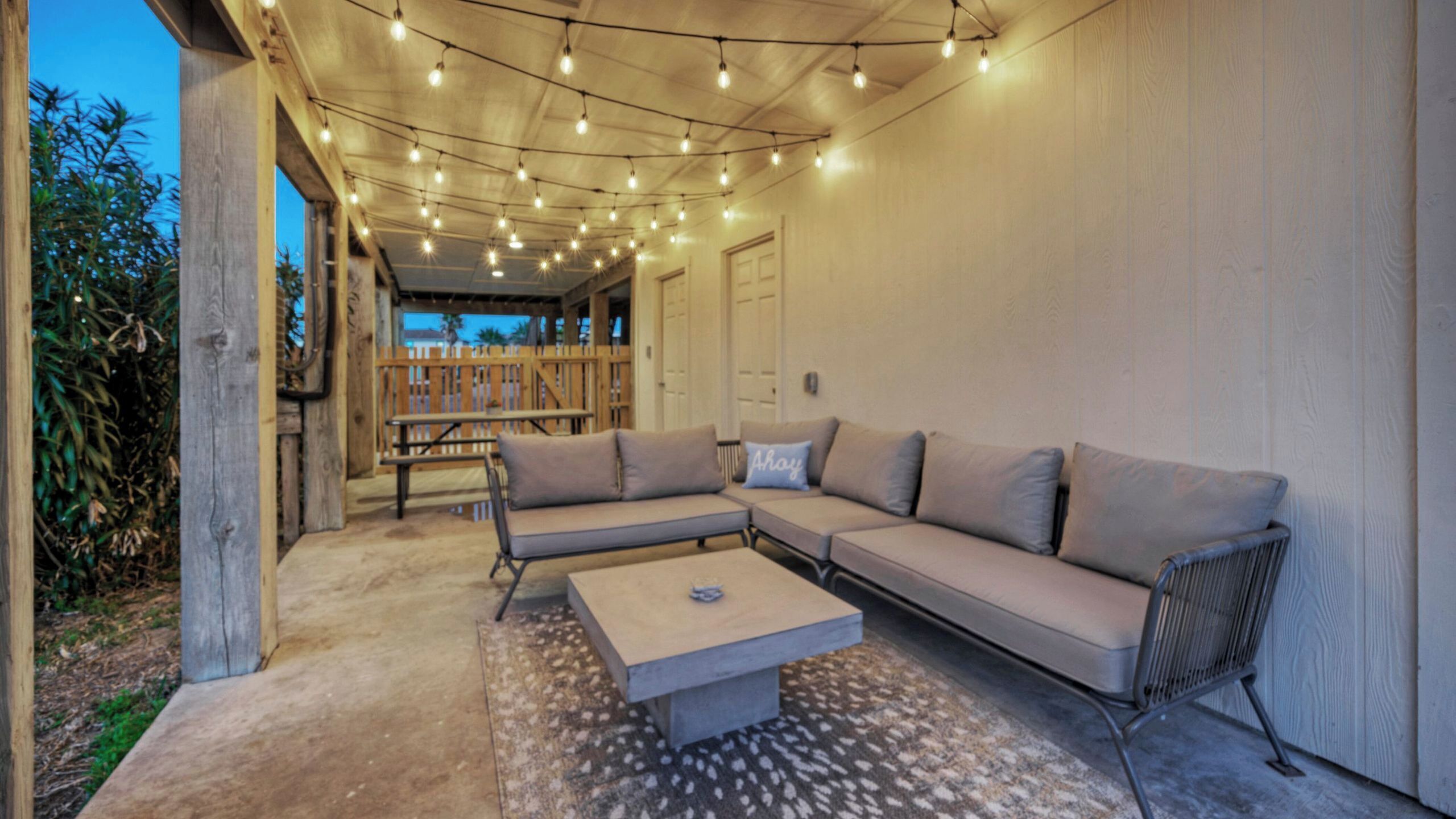 An outdoor seating area with a sofa, a table, and string lights.