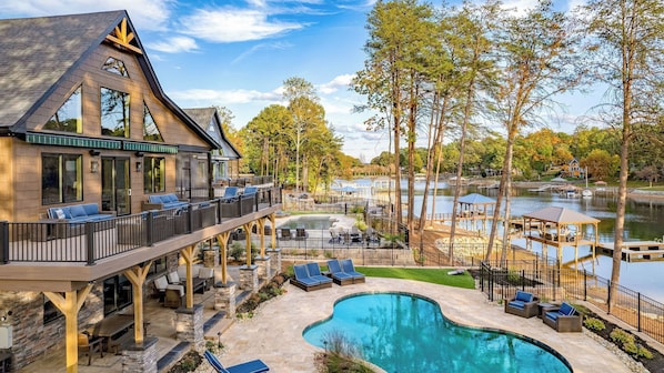 Une maison moderne dotée d’une piscine, d’un espace salon extérieur et offrant une vue sur un lac.