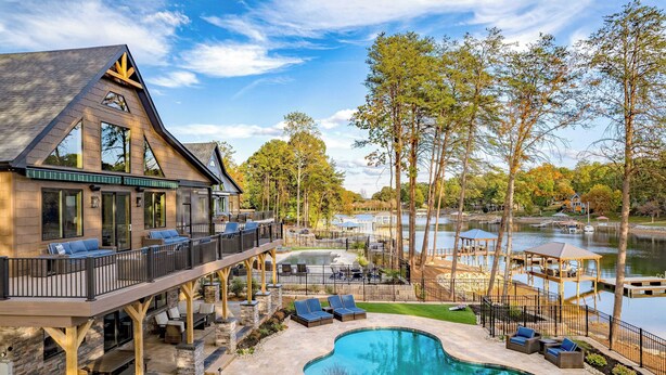 A modern house with a large deck, a swimming pool, and a view of a lake. - Luxe Lakefront Retreat w/ Pool, Hot Tub, Theater & Private Dock Sleeps 20+ (Sherrills Ford)