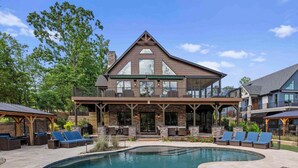 A two-story house with a large balcony, a swimming pool, and outdoor seating. - Luxe Lakefront Retreat w/ Pool, Hot Tub, Theater & Private Dock Sleeps 20+ (Sherrills Ford)