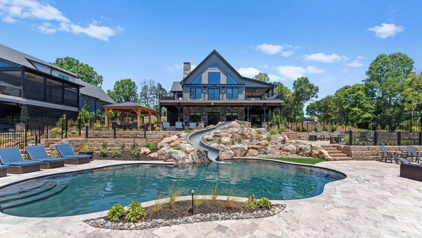 Ein geräumiges Haus mit Pool, Rutsche und Außenbereich mit Sitzgelegenheiten.