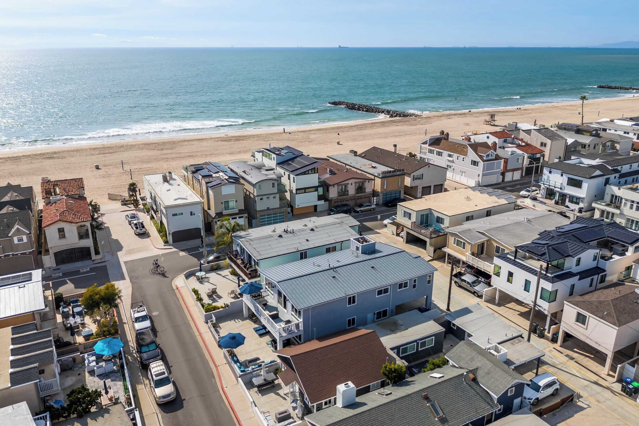 A coastal residential area with houses, a beach, and a pier.