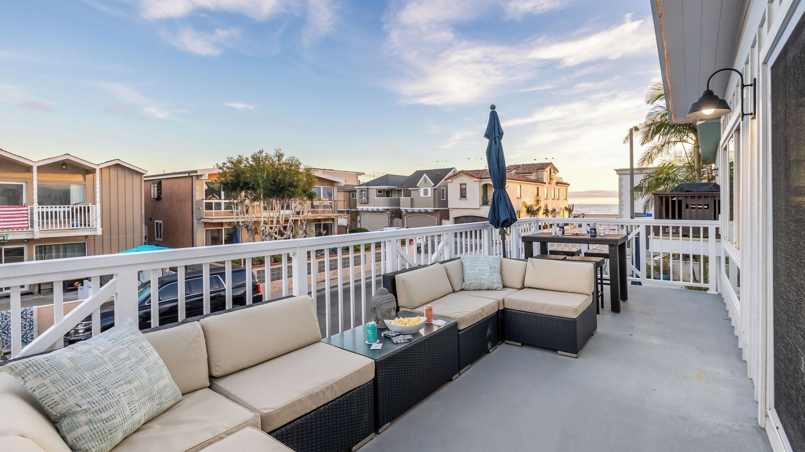 A balcony with a sofa, a table, and an umbrella.