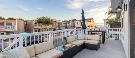 A balcony with a sofa, a table, and an umbrella.