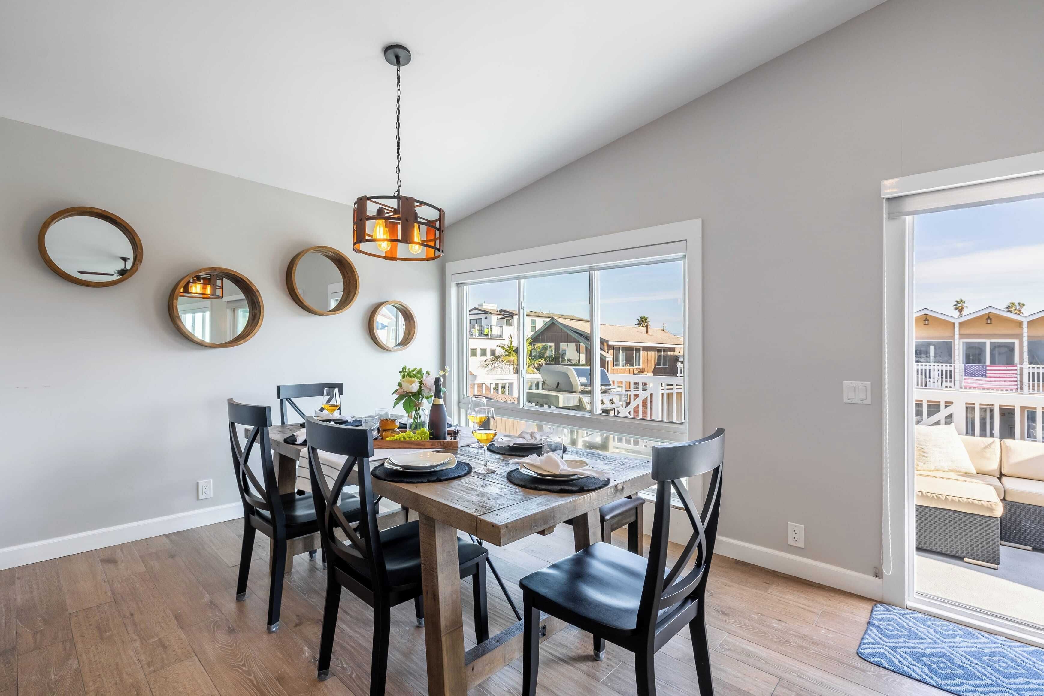A dining area with a wooden table, black chairs, and a hanging light fixture.