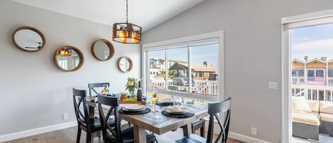A dining area with a wooden table, black chairs, and a hanging light fixture.