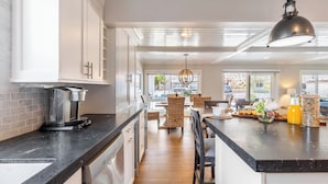 A modern kitchen with a central island, built-in appliances, and a dining area with wicker chairs.