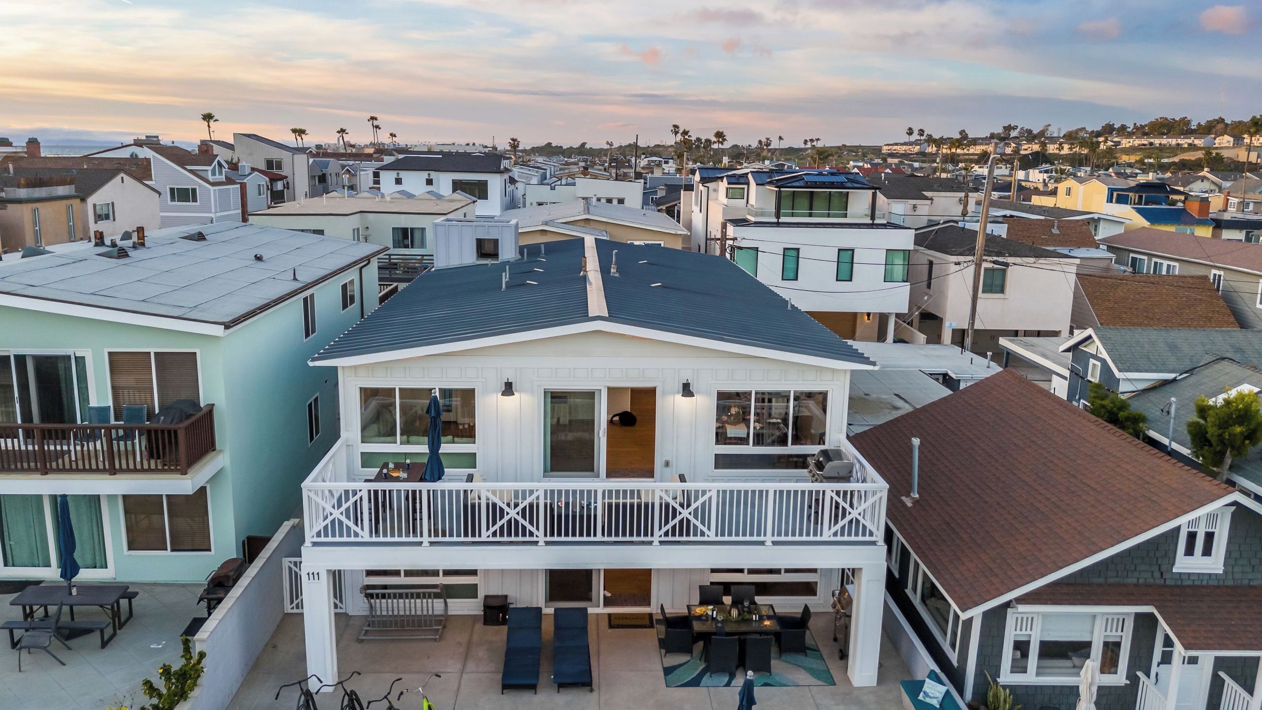 Un immeuble résidentiel doté d’un balcon, d’une terrasse avec des sièges et offrant une vue sur le quartier environnant.