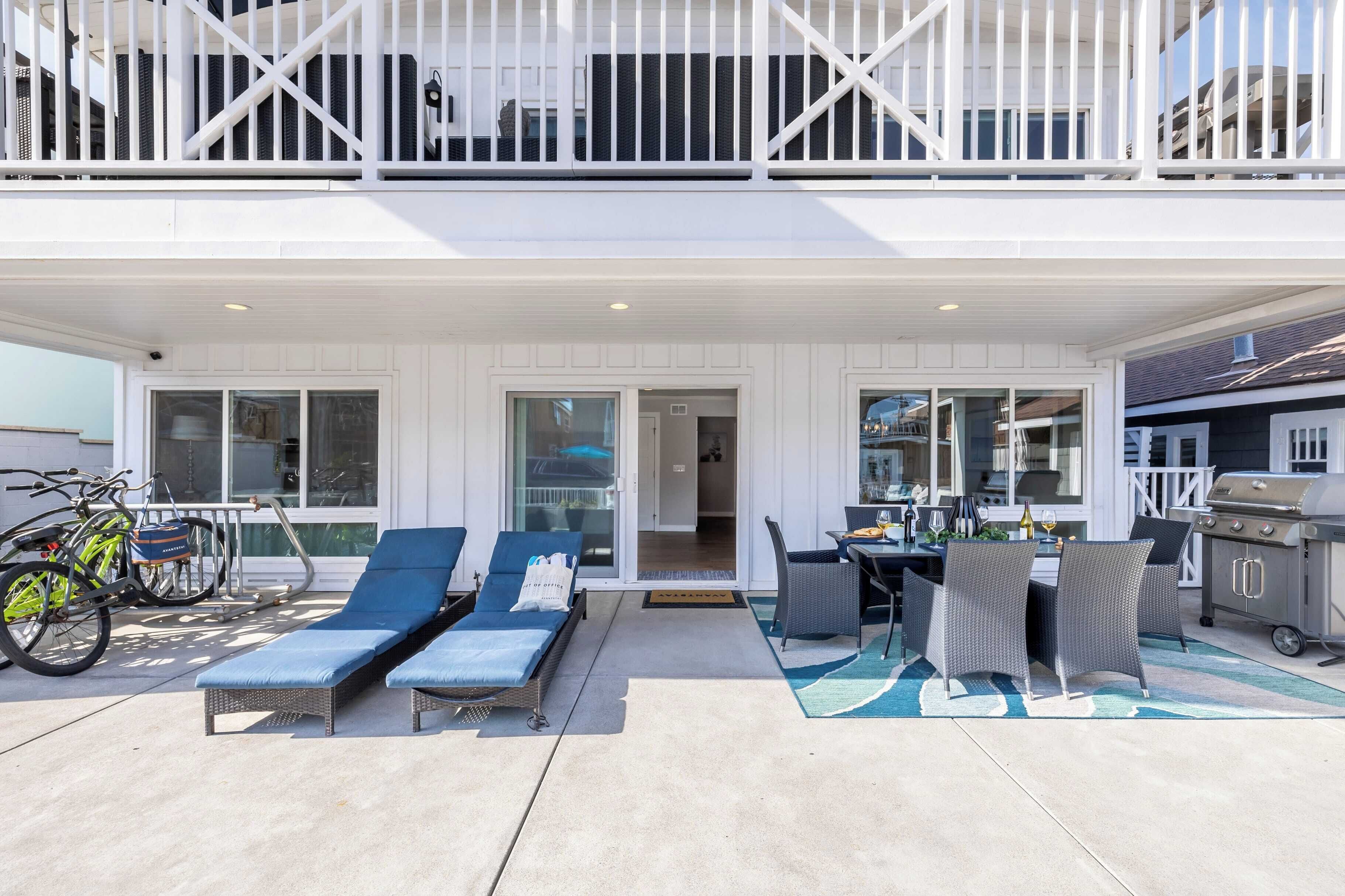 A covered outdoor patio with lounge chairs, a dining table, and a grill.