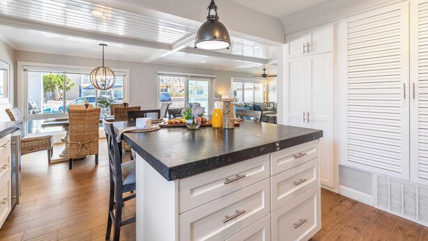 A spacious kitchen with a large island, white cabinetry, and a hanging pendant light.