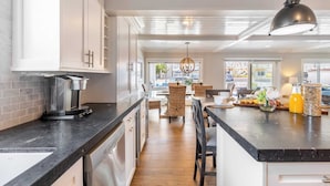 A modern kitchen with white cabinets, a black countertop, and a central island with seating.