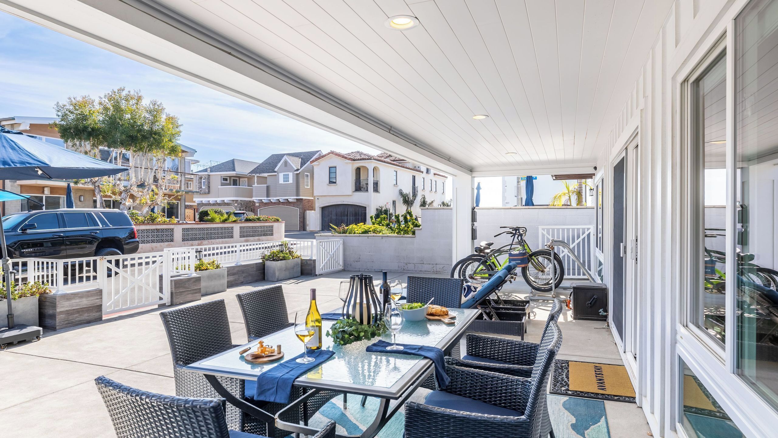 A covered patio with outdoor furniture, a table set for dining, and a bicycle parked nearby.