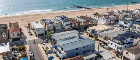 A coastal residential area with houses, a beach, and a pier.