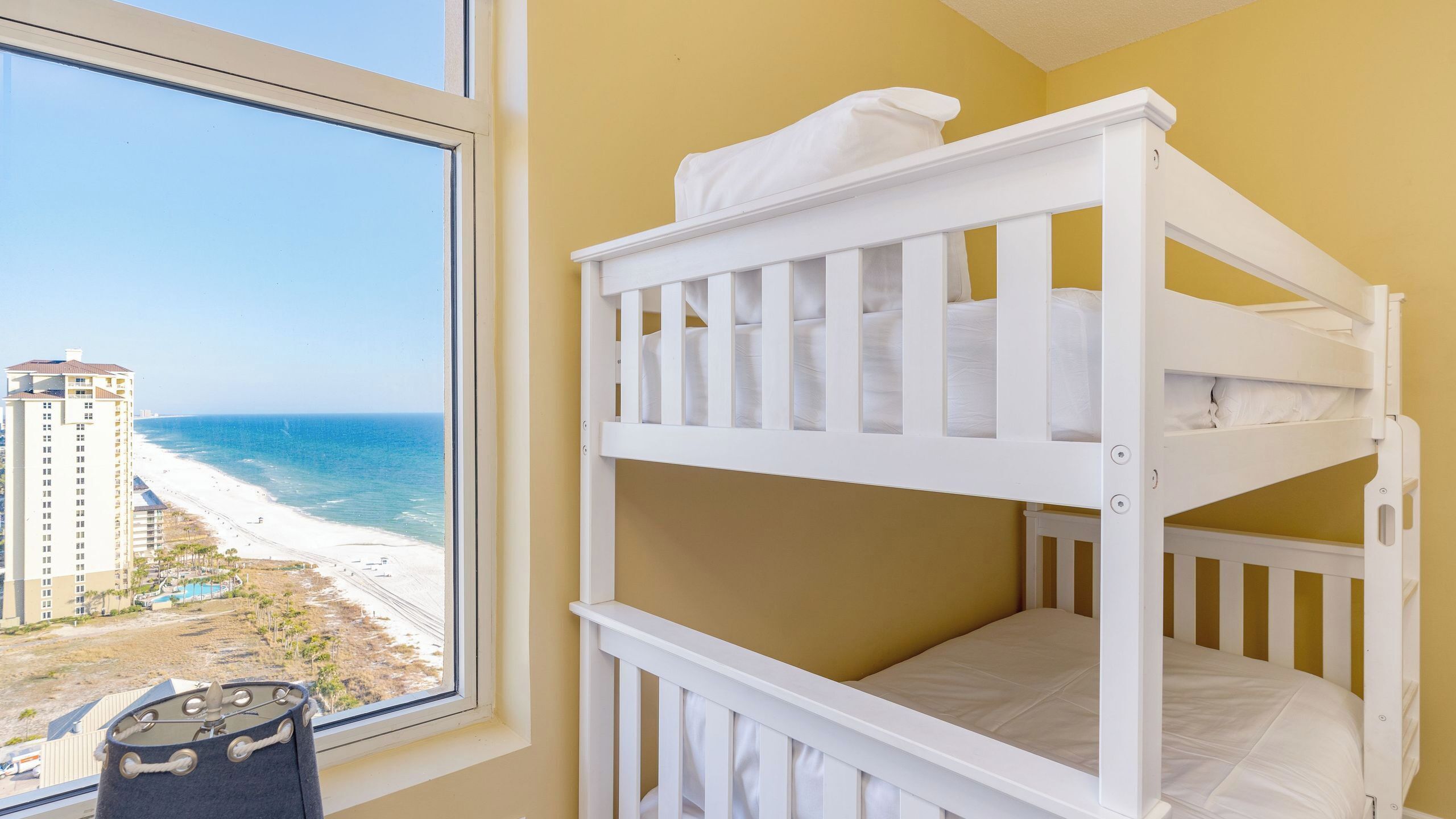 Uma cama beliche com vista para a praia e um edifício alto.