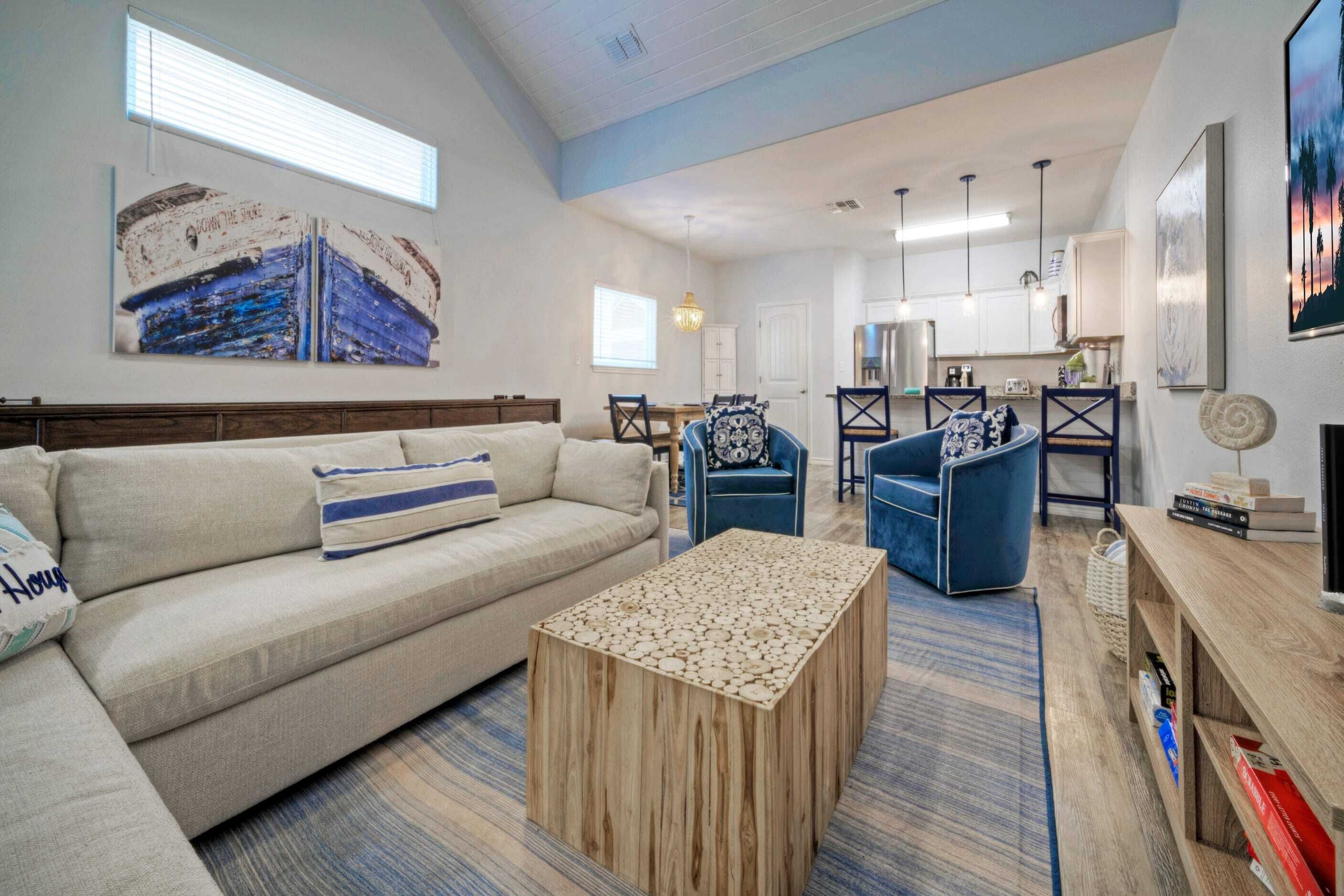 A spacious living area with a sofa, a coffee table, and a dining area with chairs.