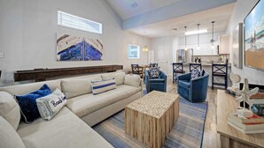 Een ruime woonkamer met een grote bank, een salontafel en een eethoek met stoelen en een tafel.