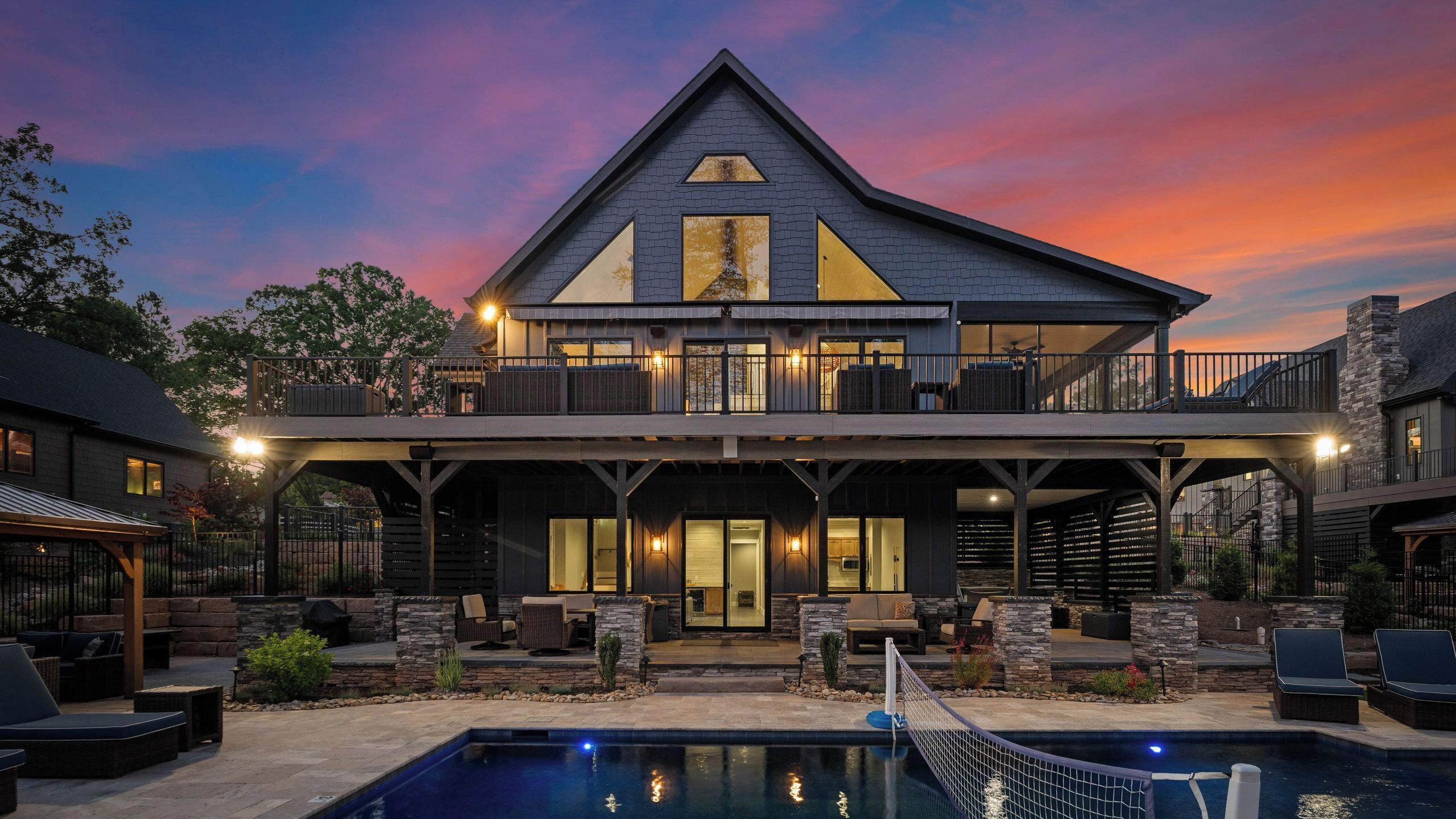 Ein zweistöckiges Haus mit Pool, Außenbereich und Sonnenuntergangshimmel.