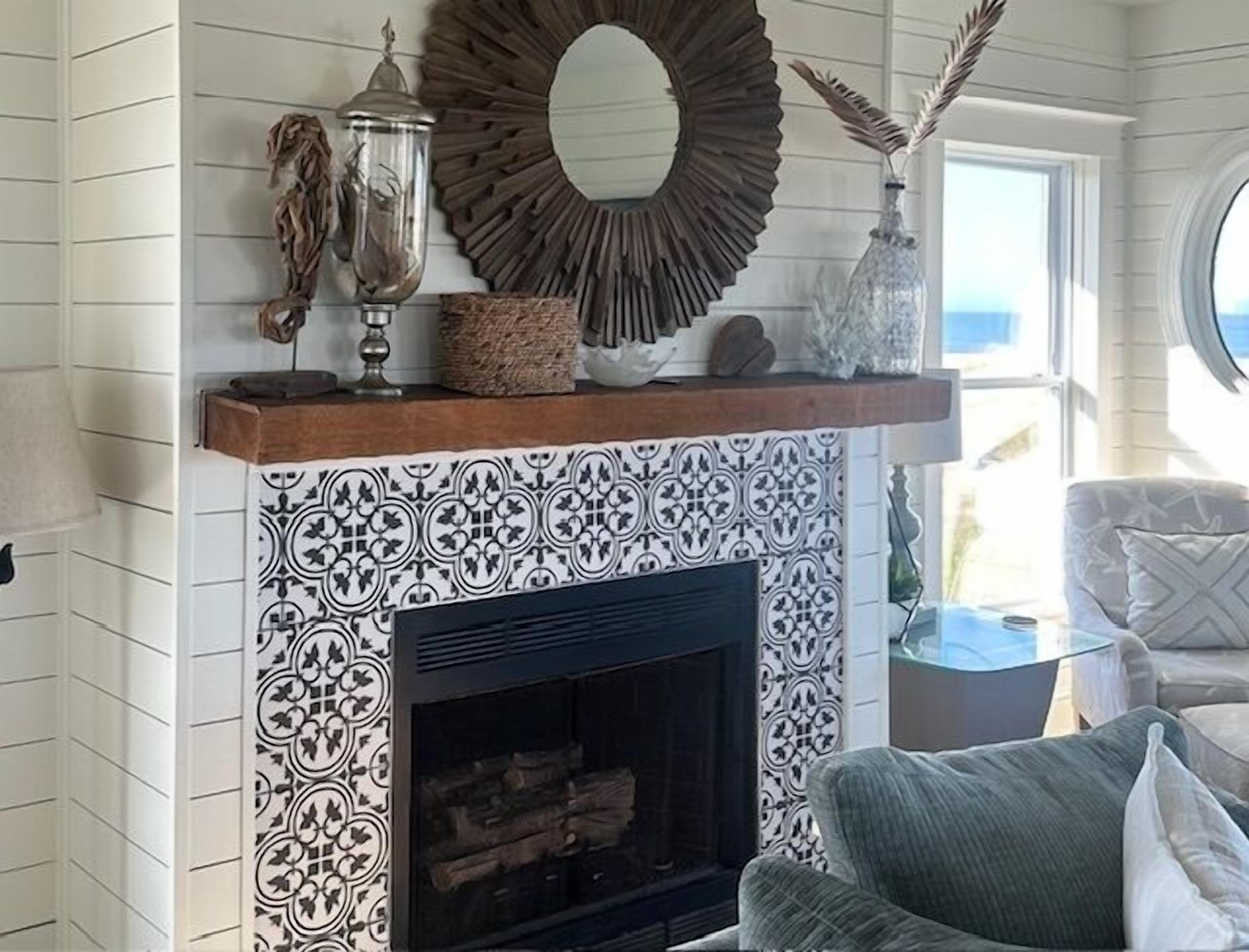 A fireplace with patterned tiles, a mirror, and decorative items on the mantel.