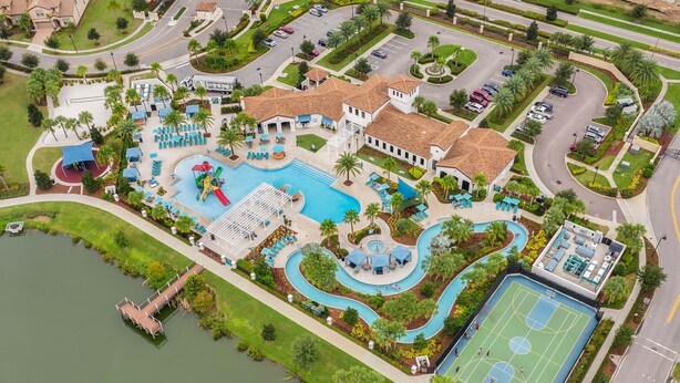 An aerial view of a resort with a swimming pool, tennis court, and landscaped areas.