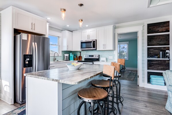 A modern kitchen with a large island, stainless steel appliances, and bar stools.