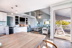 A spacious kitchen with white cabinets, a wooden dining table, and a staircase leading to a balcony.