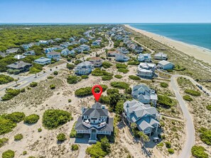An aerial view of a coastal residential area with houses, roads, and a beach.