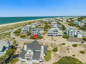 A coastal residential area with beachfront properties, a clear sky, and a red location marker.