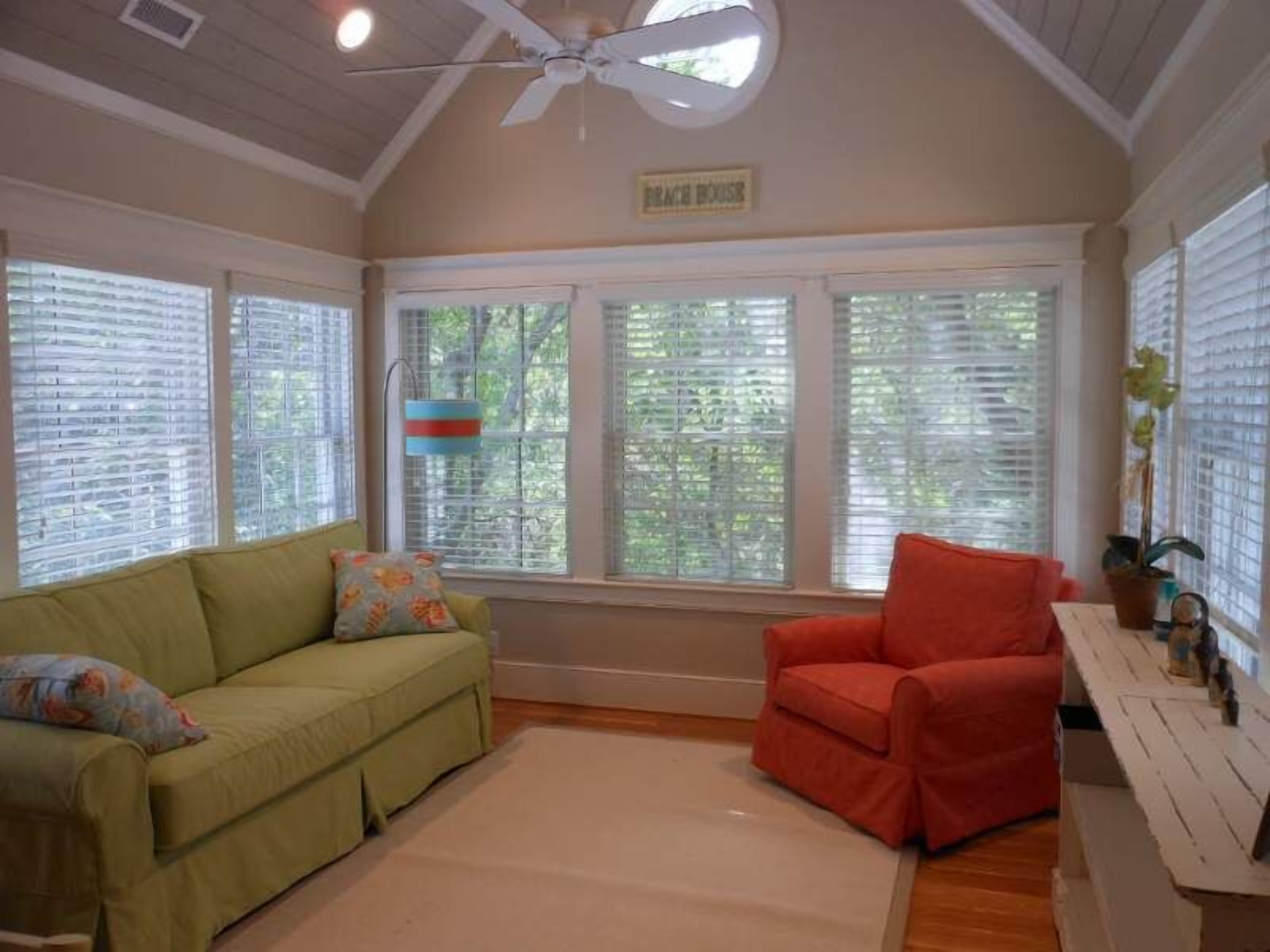 A room with a green sofa, a red chair, and a white table with a plant.