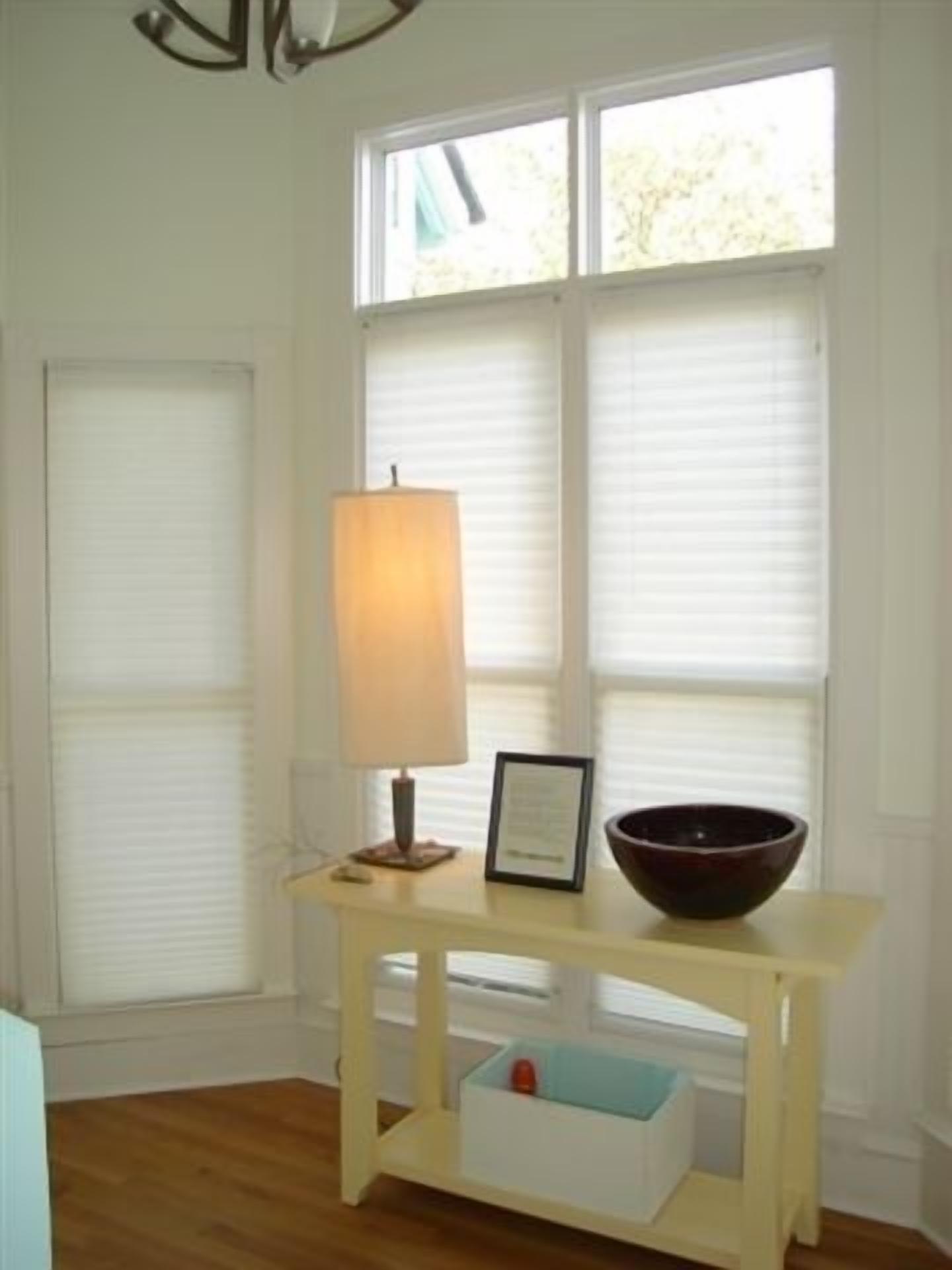 A room with a wooden table, a lamp, a framed certificate, and a bowl.