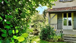 A house with a garden, a wooden porch, and a stone wall.