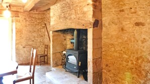 A rustic stone interior with a wood-burning stove, a wooden chair, and a tiled floor.