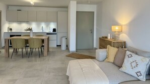 Un appartement moderne comprenant un coin repas, une kitchenette et un salon avec un canapé et une lampe.
