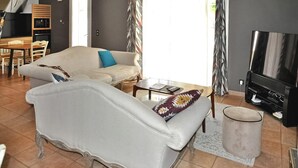 Un salon avec un canapé, une table basse, un téléviseur et une poubelle.