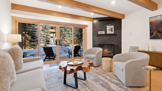 A modern living room with a fireplace, comfortable seating, and a large window overlooking a snowy outdoor area. - Riverside Getaway | Walk to Main St, Festival & Ski Fun (Telluride)
