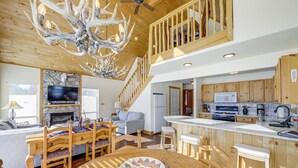 Ein großzügiger Wohnbereich mit Kamin, Holzesstisch und einer großen Chandelüster.