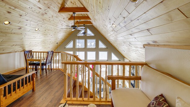 Ein Loft-Zimmer mit Holzboden, einer Holztreppe und einem großen Fenster.