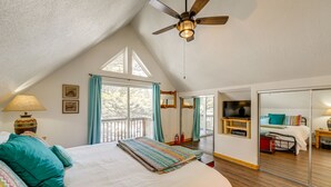 Ein Schlafzimmer mit einem großen Bett, einem Deckenventilator und Blick durch ein Fenster.