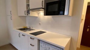 A compact kitchen with a built-in washing machine, a microwave, and a sink. - Colorful NoLo Studio (Milano)