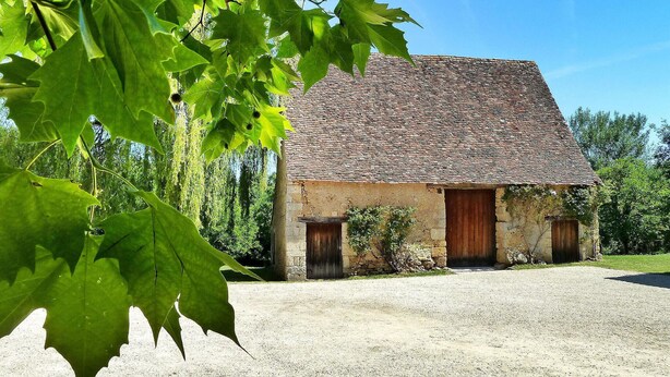 A rustic stone building with a sloped roof, two wooden doors, and a gravel driveway. - Beautiful home in Lamonzie Montastruc (Lamonzie Montastruc)