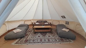 Een tent met twee slaapgedeeltes, een centrale tafel en een kamerkleed met een patroon.
