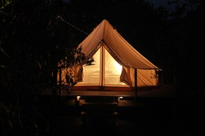 A tent with a central entrance, surrounded by a wooden deck, and illuminated by string lights. - La Templanza EcoGlamping Cultural (Oceania del Polonio)