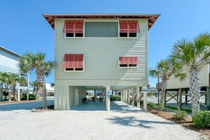 A two-story building with red shutters, a covered walkway, and palm trees.
