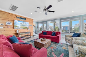 A spacious living room with a red sofa, a patterned armchair, and a wooden coffee table. - Sandy Cheeks | Outdoor Pool | Waterfront | My Beach Getaways (Gulf Shores)