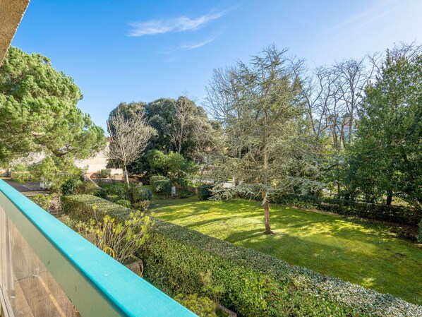 Ein gepflegter Garten mit verschiedenen Bäumen und Sträuchern, einem ordentlich geschnittenen Rasen und blauem Himmel.