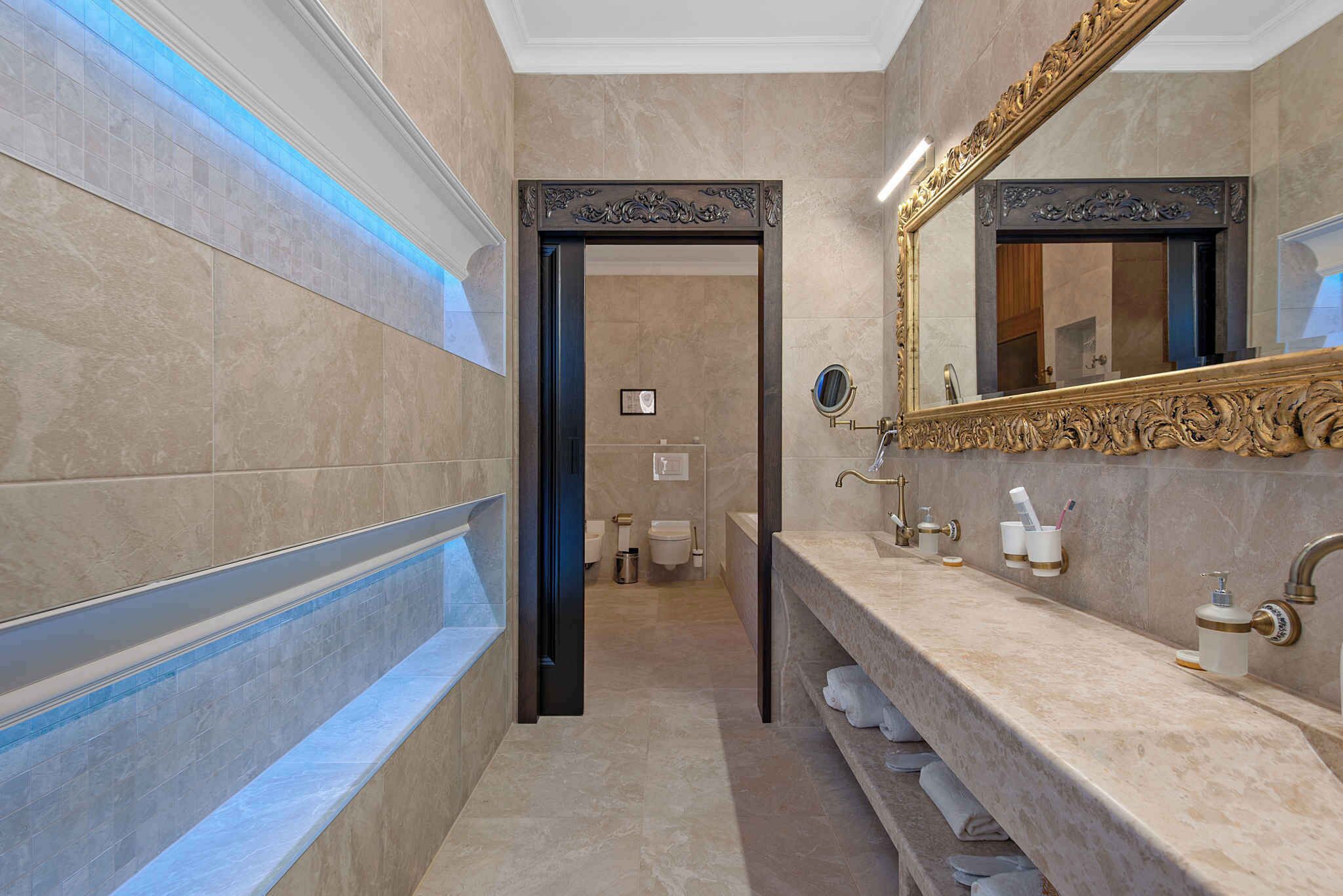 Une salle de bain moderne avec un grand miroir, un meuble-lavabo et un porte-serviettes.