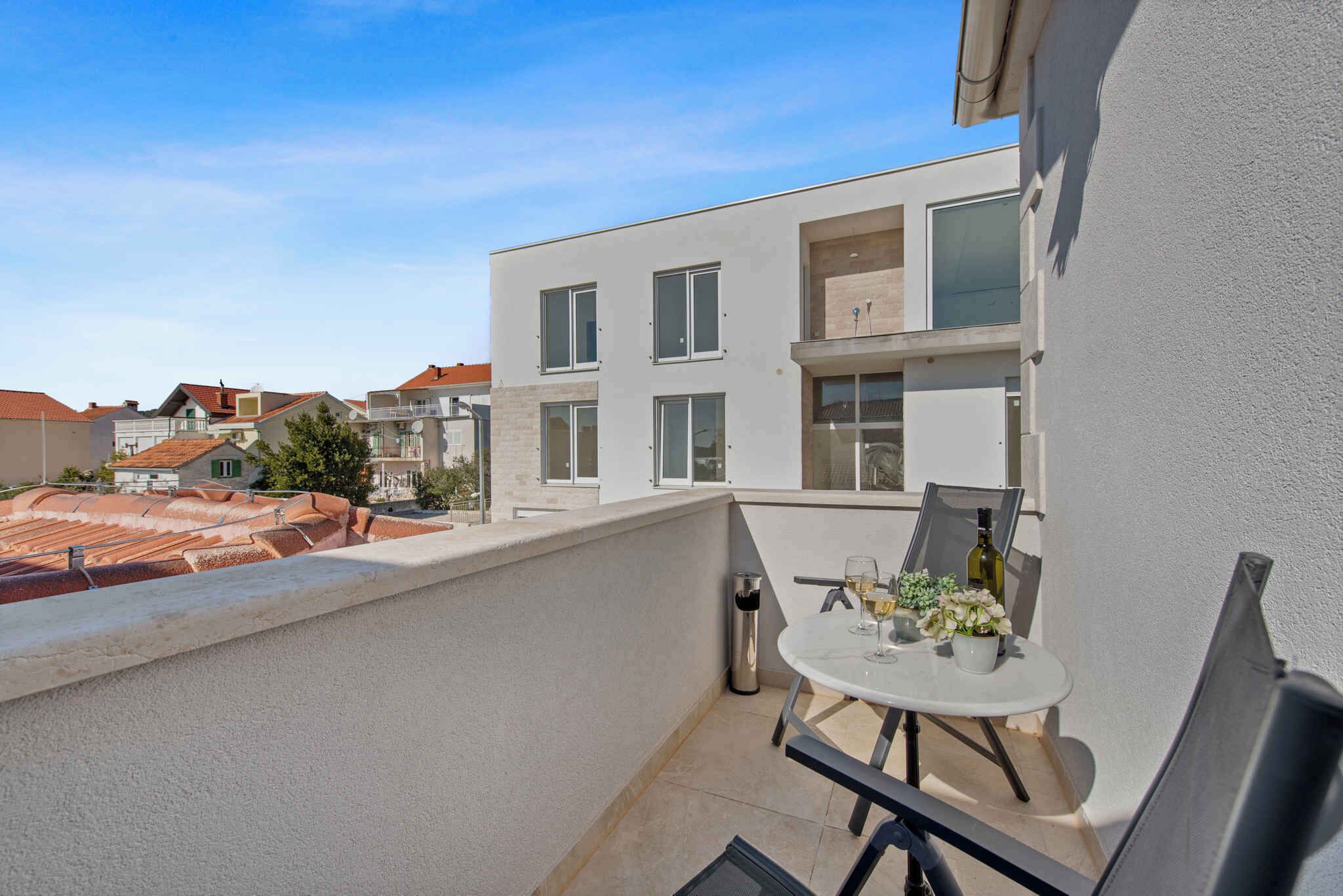 A balcony with a table and chairs, a bottle of wine, and a small potted plant.