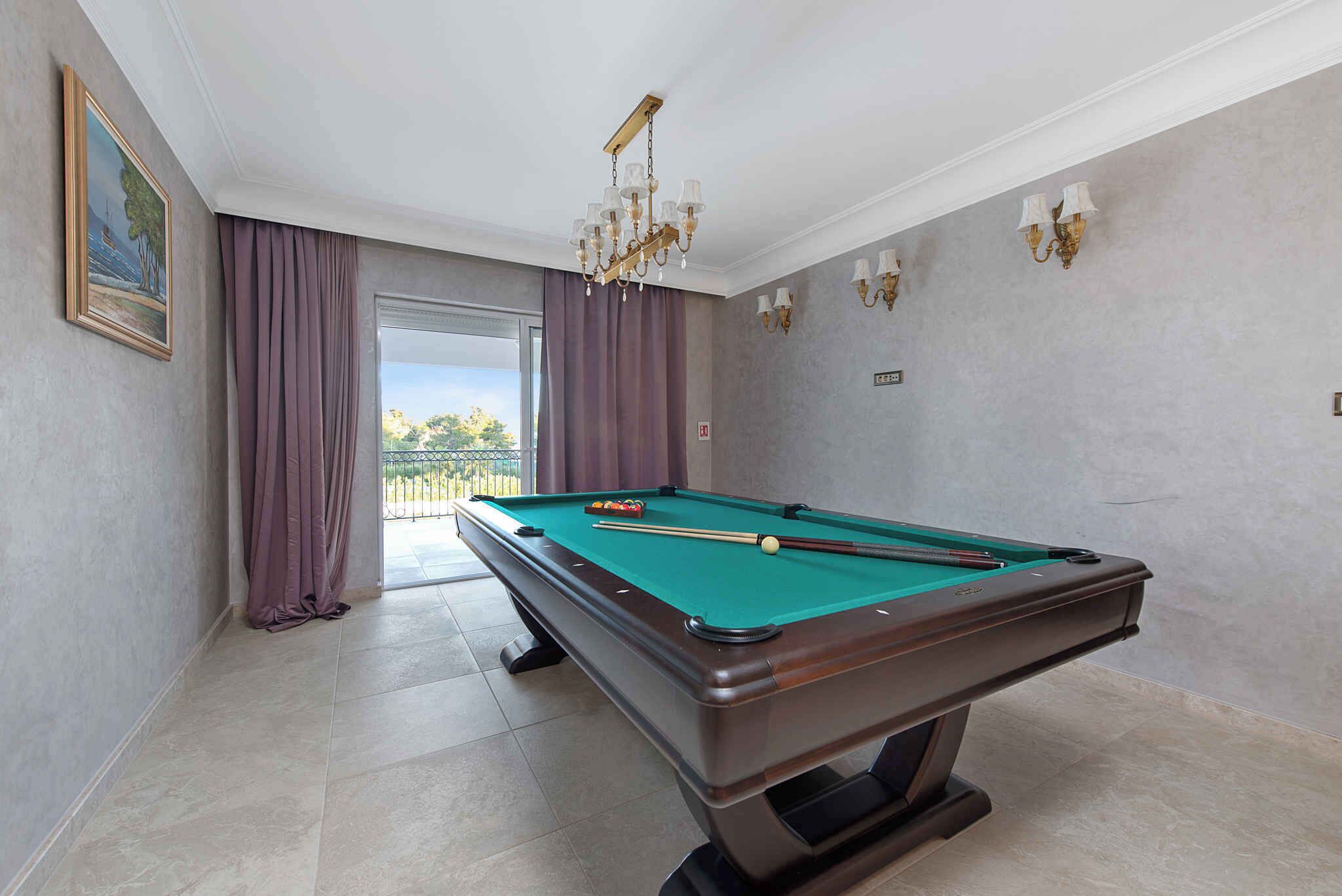 Une table de billard dans une pièce avec vue, des rideaux et des appliques murales.
