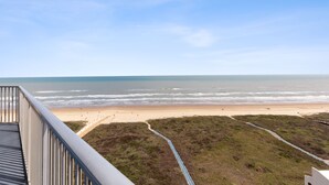 Vista de la playa desde un balcón, con un sendero que lleva a la orilla.
