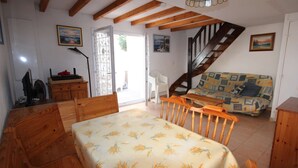 Une pièce chaleureuse avec un lit en bois, une table à manger, un escalier et un canapé.