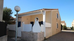 Un immeuble résidentiel avec un toit recouvert de tuiles, une clôture blanche et une base en béton.